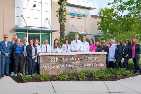 A group of doctors standing in front of a sign
Description automatically generated